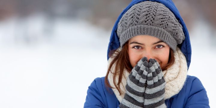 Woman outside in snow with coat, hat and gloves on