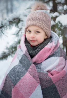 Child wrapped up in a blanket, coat and hat outside