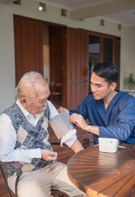 A health care worker taking the blood pressure or an elderly man