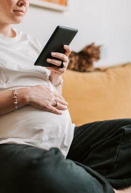 A pregnant woman looking at her phone.