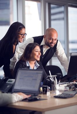 People working at a desk looking at a computer