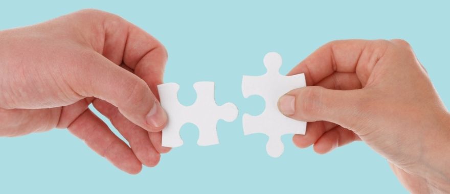 Two hands holding puzzle pieces that slot together