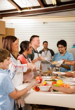 A group of people surrounding a table with fruit on it