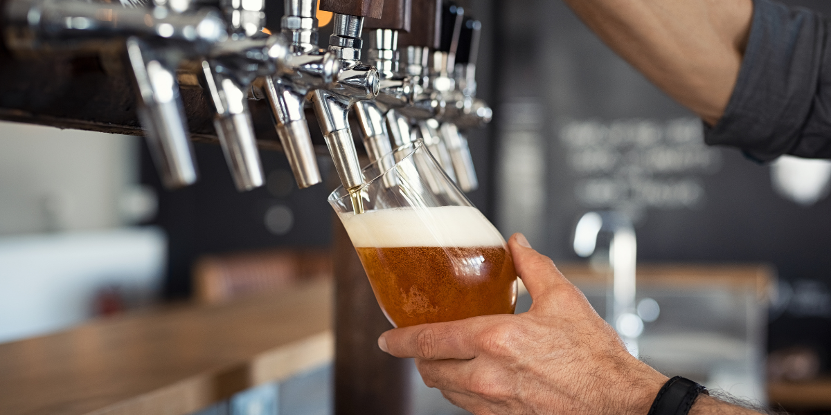 Someone pouring a glass of draught beer.